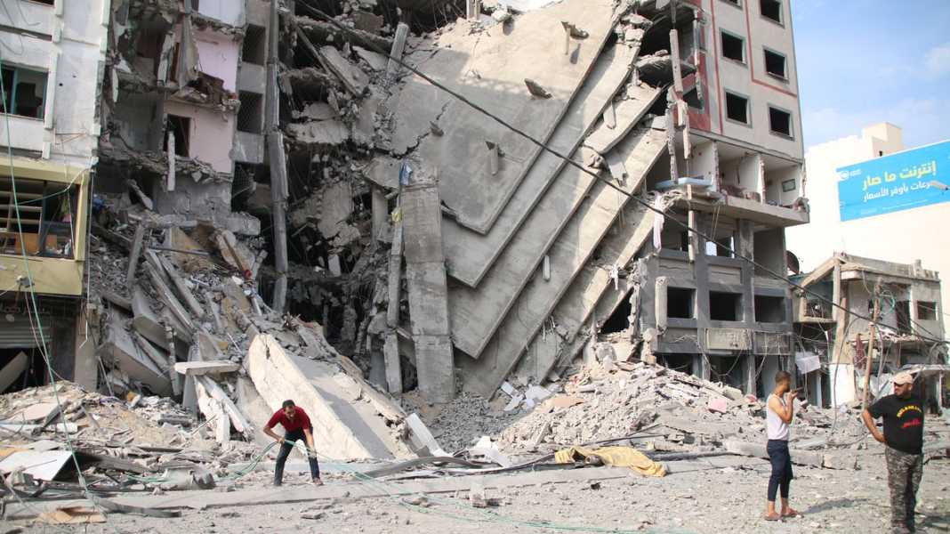 People are seen in front of a ruined building.