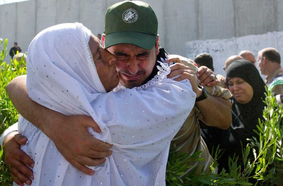 Al Loh, dressed in a green ball cap and came shirt, seems to hold back tears, his face tight and eyes closed as his mother, dressed all in white, hugs him tightly and kisses his cheek.