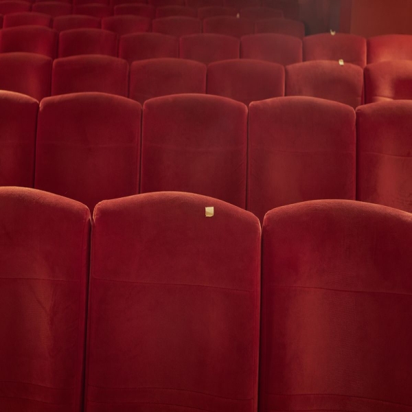 Red velvet theater seats in row, some with a small square of yellow tape.