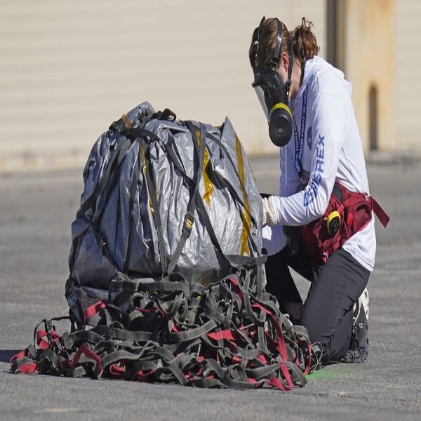 Person wearing a face mask examines a capsule that is blanketed and covered in a net