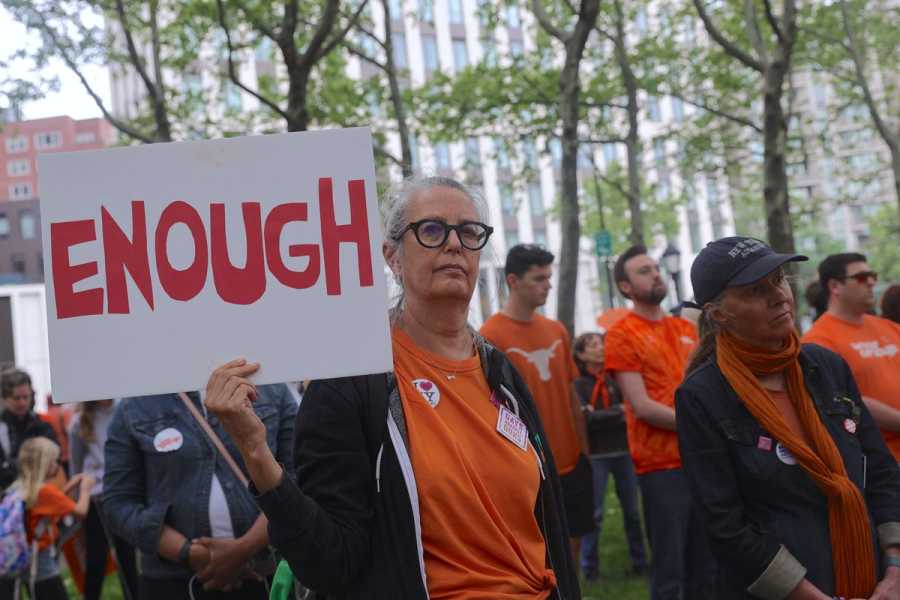 People walk across the Brooklyn Bridge in an effort to end gun violence. One holds up a hand-lettered sign that reads, “Enough.”