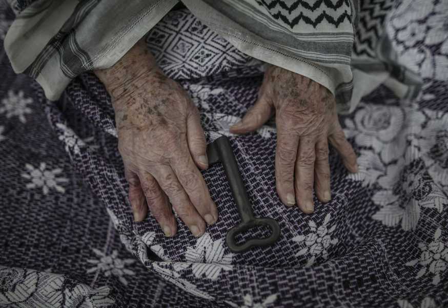 An elderly woman’s fingers flatten a floral black and white woven cloth. Between her hands lies a large old-fashioned iron key. This photo was taken at the Palestinian refugee camp in Jabalia, northern Gaza Strip, on May 13, 2018. 