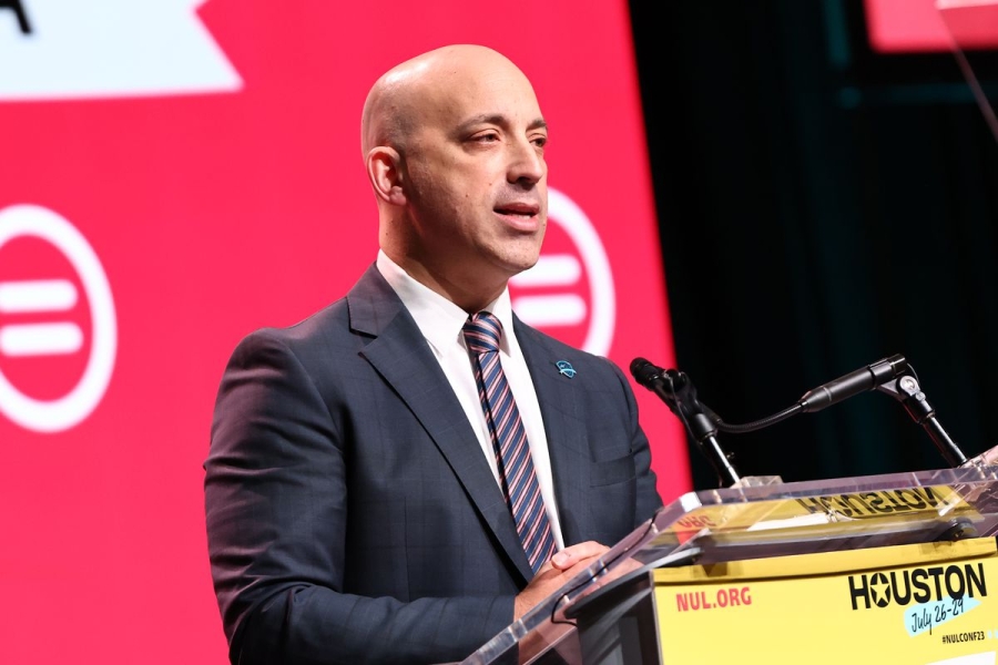 The ADL CEO speaks on a podium in front of a red background.