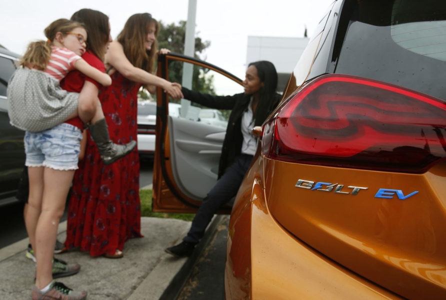 An orange Bolt EV all-electric car at a Chevrolet dealership in Fremont, California.