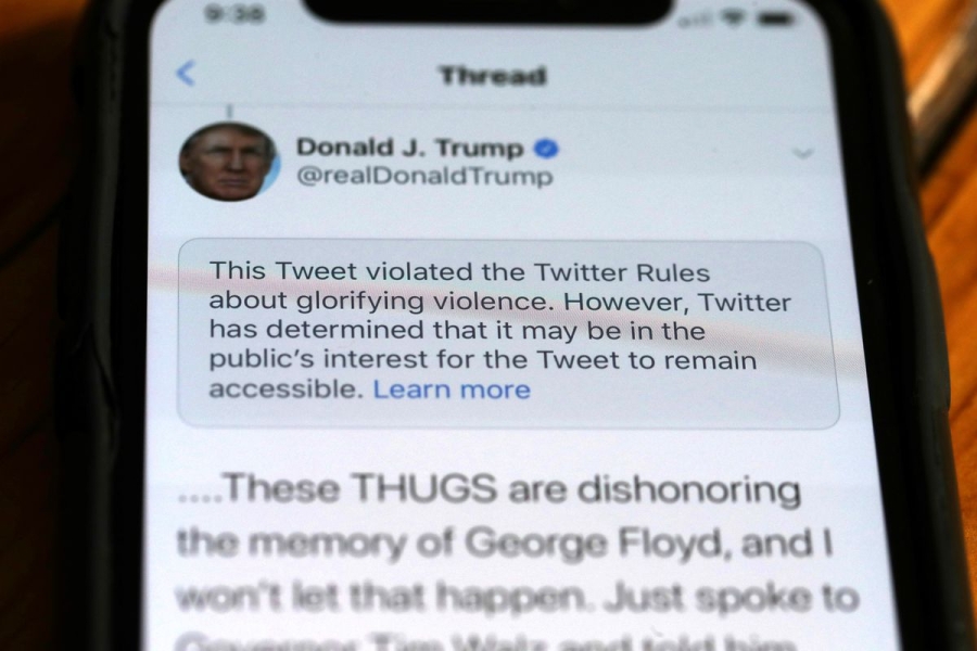 A photo of a phone displaying a Trump tweet that says “These thugs are dishonoring the memory of George Floyd and I won’t let that happen” and the tweet has a warning above it saying the post violated Twitter rules.