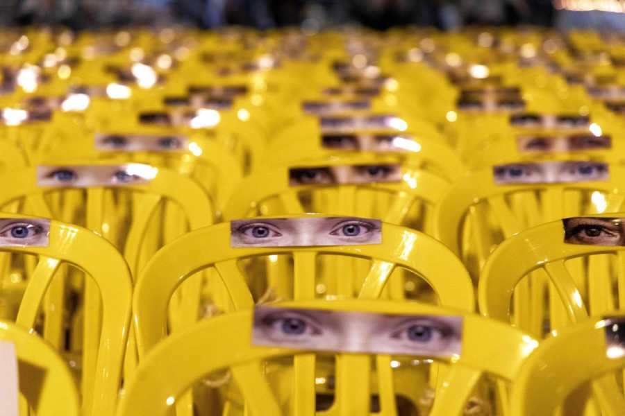 A field of yellow plastic chairs with human eyes.