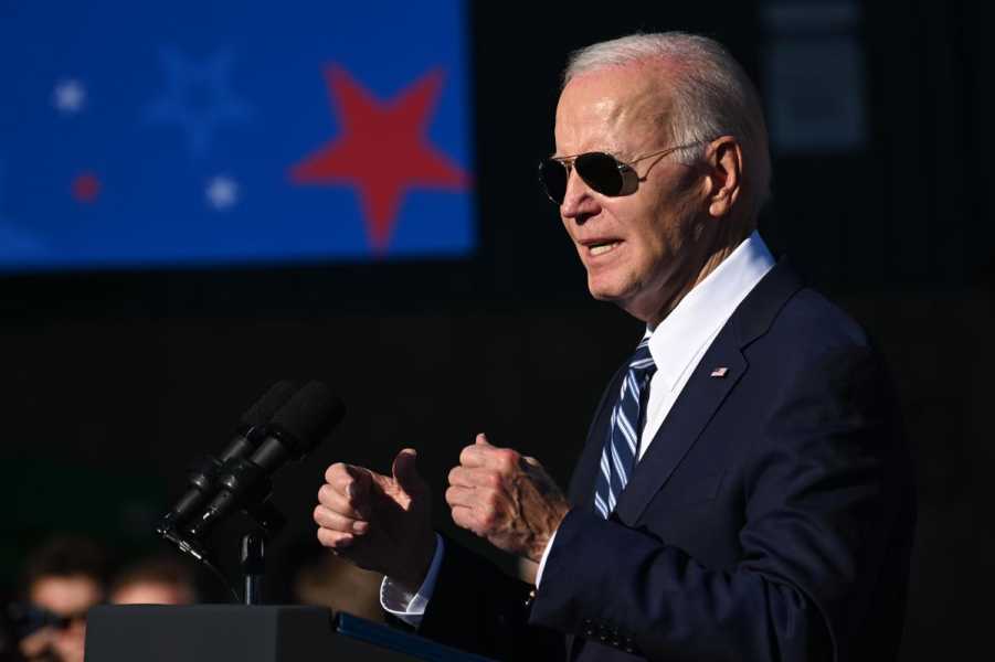 Biden speaks at a podium while wearing sunglasses.