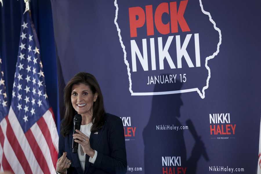 Nikki Haley holds a microphone while standing in front of a backdrop that reads “Pick Nikki January 15.”