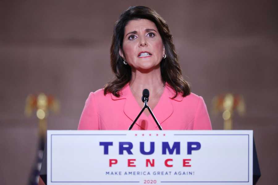Nikki Haley speaks at a lecture with the Trump/Pence logo on it