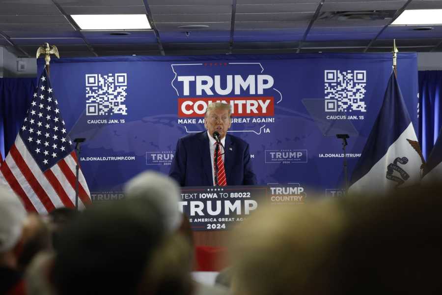 Donald Trump speaking into a microphone in front of a banner declaring “Trump country: Make America great again.”