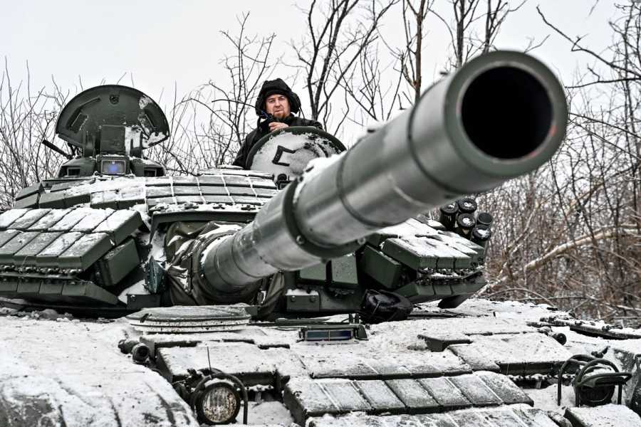 A soldier sits in the turret of a tank.