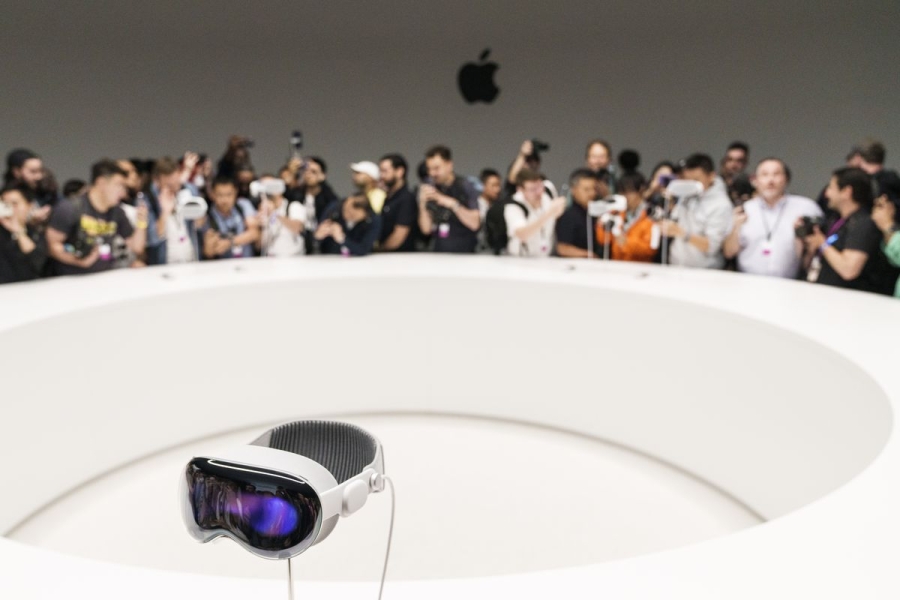 The Apple Vision Pro headset sits on a stand at the far side of a ring as a crowd looks at it from afar in Cupertino, California.