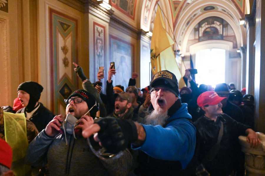 People yelling and running down a hall inside the Capitol.
