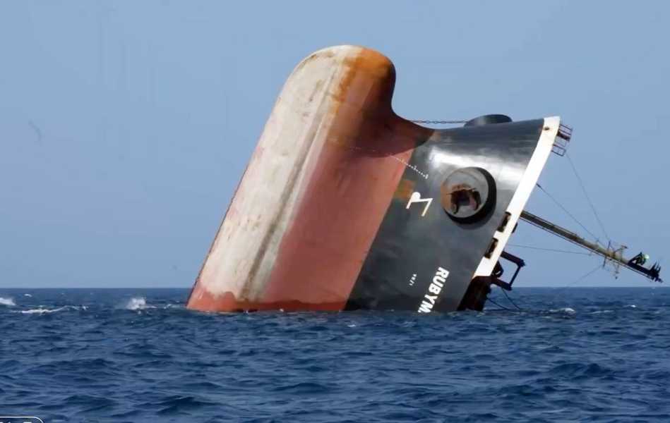 The stern of a cargo ship sinking vertically into the water.