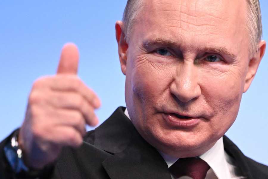 A close-up image of Putin, who lifts his hand in a thumbs-up gesture. 