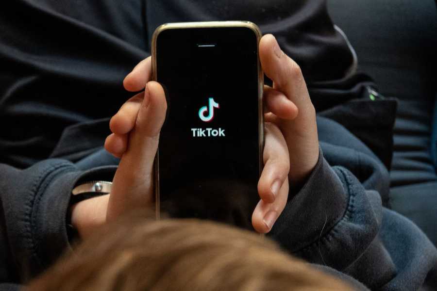 A phone held in two hands displays the TikTok logo.