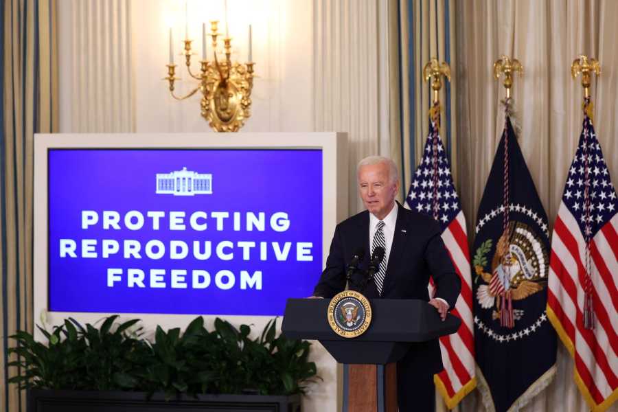 President Joe Biden speaks at a lectern beside a sign that reads “Protecting reproductive freedom.”