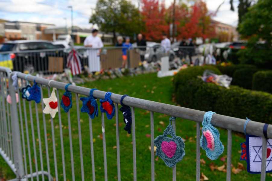 Stars of David in blues, pinks, and reds hang on a metal barricade.