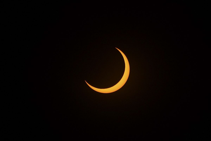 A partial solar eclipse that shows a crescent-shaped rim of the sun against a black sky.