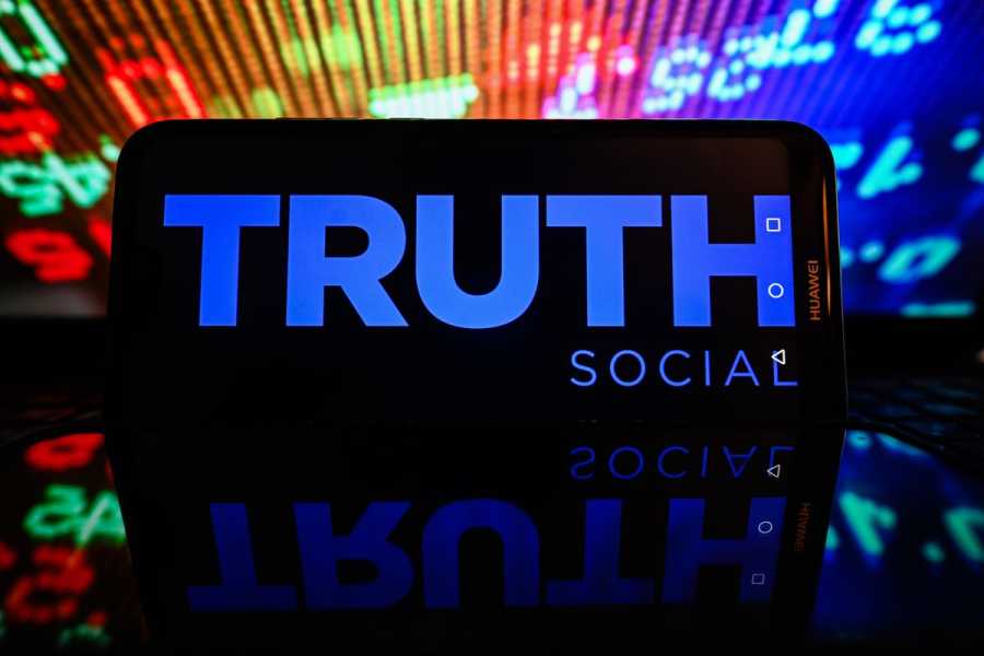 Truth Social logo is displayed on a screen with stock numbers in the background.