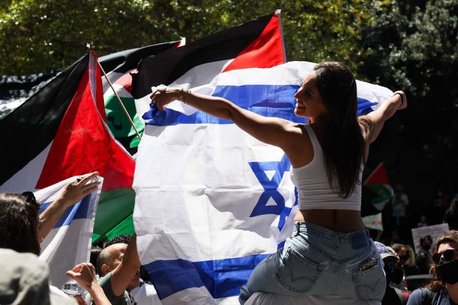 A woman protesting in support of Israel waves an Israeli flag while surrounded by pro-Palestinian counterprotesters&nbsp;with Palestinian flags.