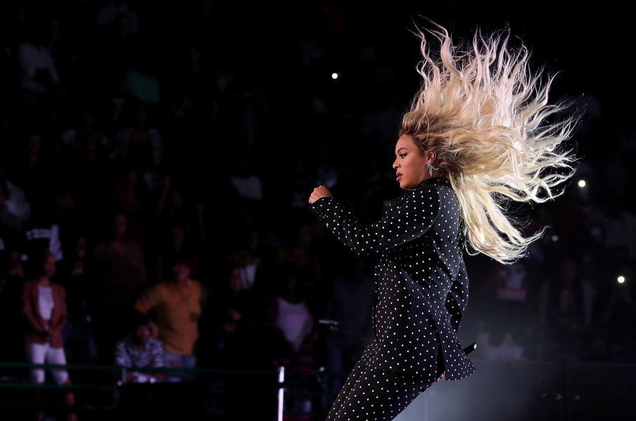 Beyoncé onstage in a black suit with white polka dots, blonde hair flying.