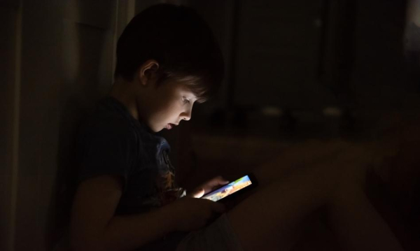 A child with their nose stuck in a screen. Nearly 40 percent of children use a smartphone, tablet, or computer.